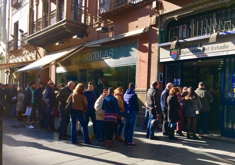 Sevillanos haciendo cola frente a una administración de Lotería.