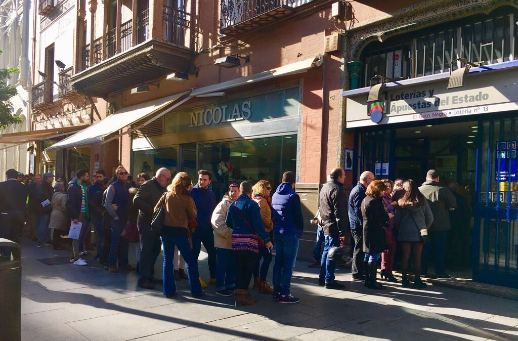 Sevillanos haciendo cola frente a una administración de Lotería.